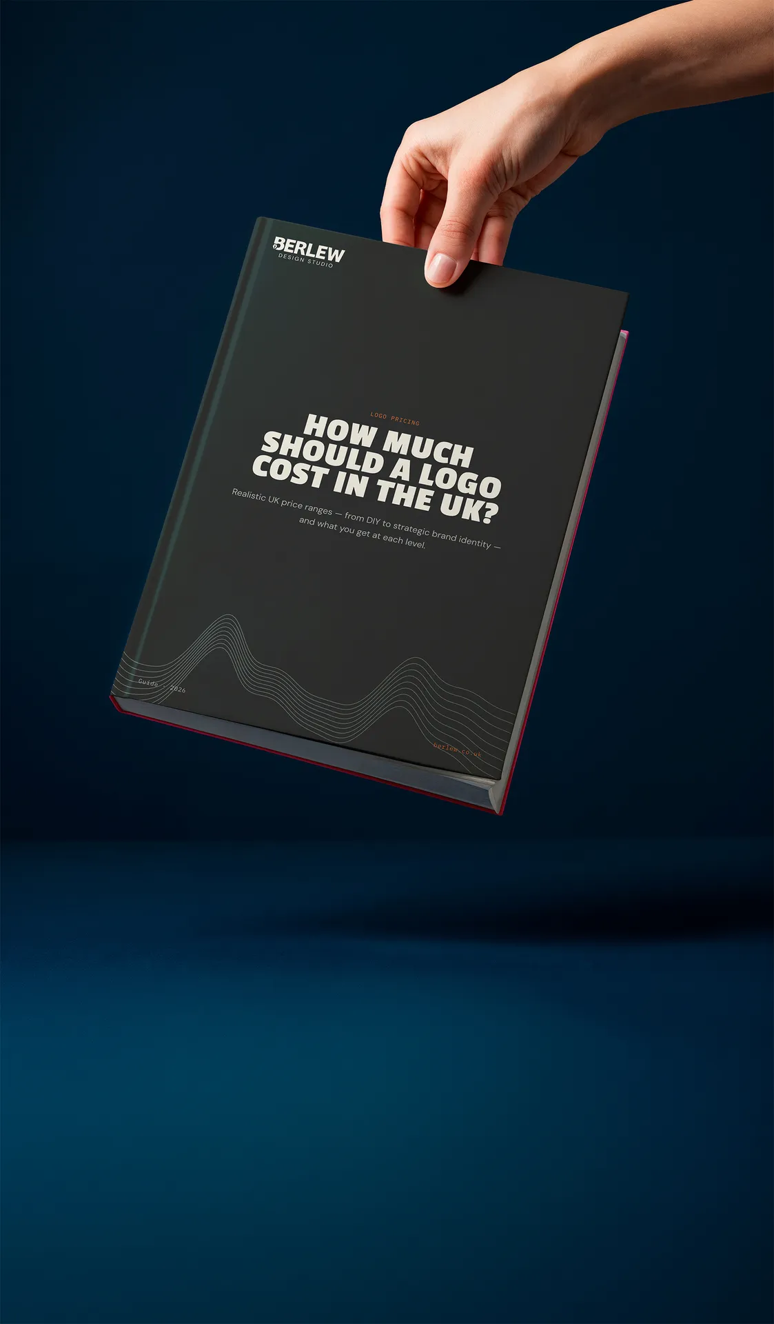 A hand holds a black book with white text that reads "HOW MUCH SHOULD A LOGO COST IN THE UK?" against a dark blue background.