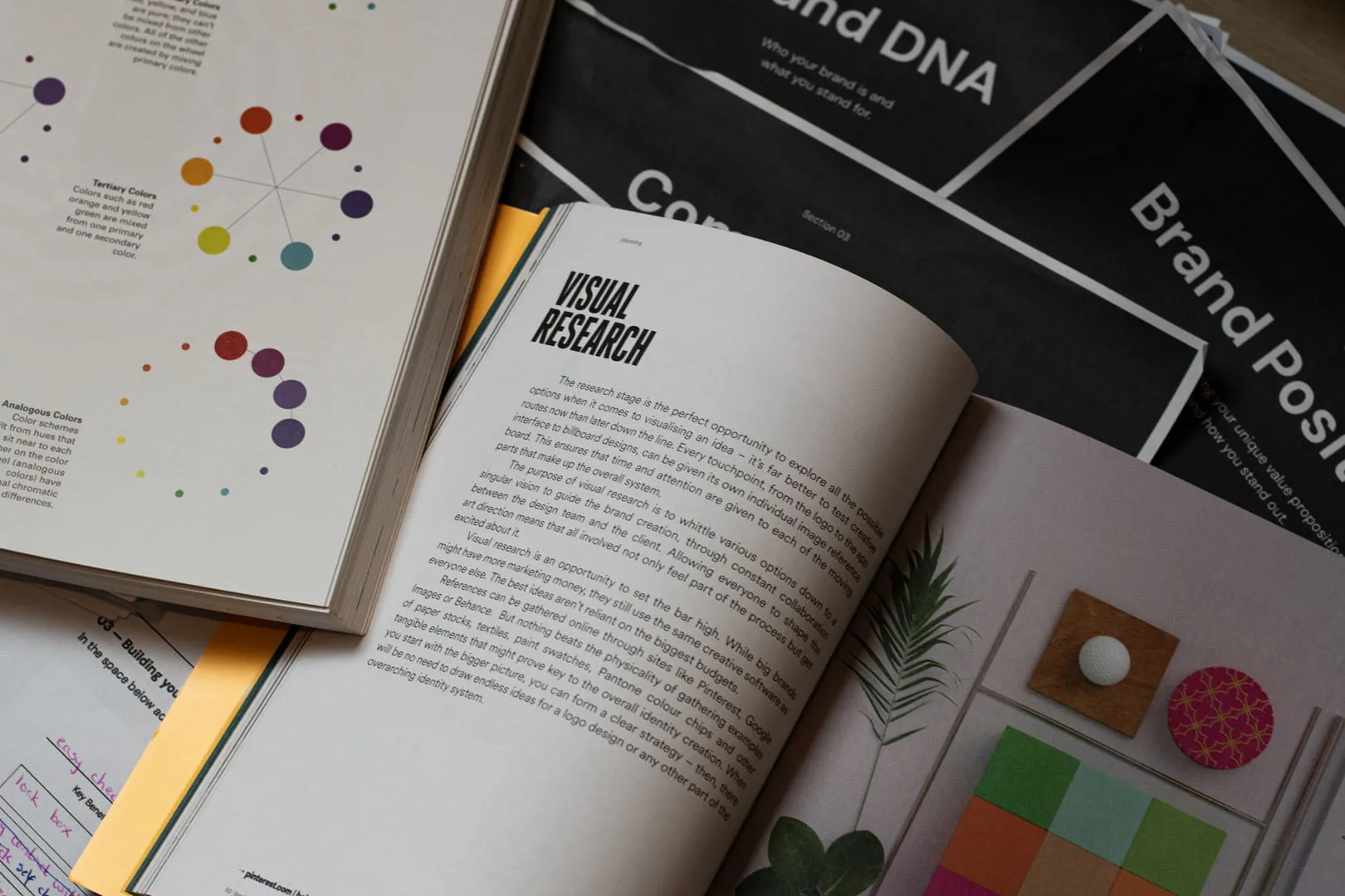 An open brand book showing visual research, type studies and a hand-bound layout in muted colours.