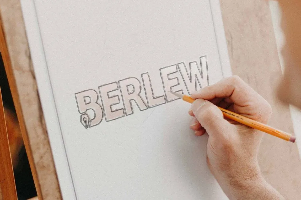 Person sketching the Berlew logo design in a notebook mockup