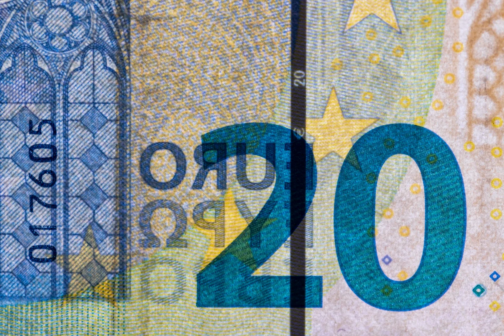 Twenty euro banknotes in a close-up stack on a neutral surface.