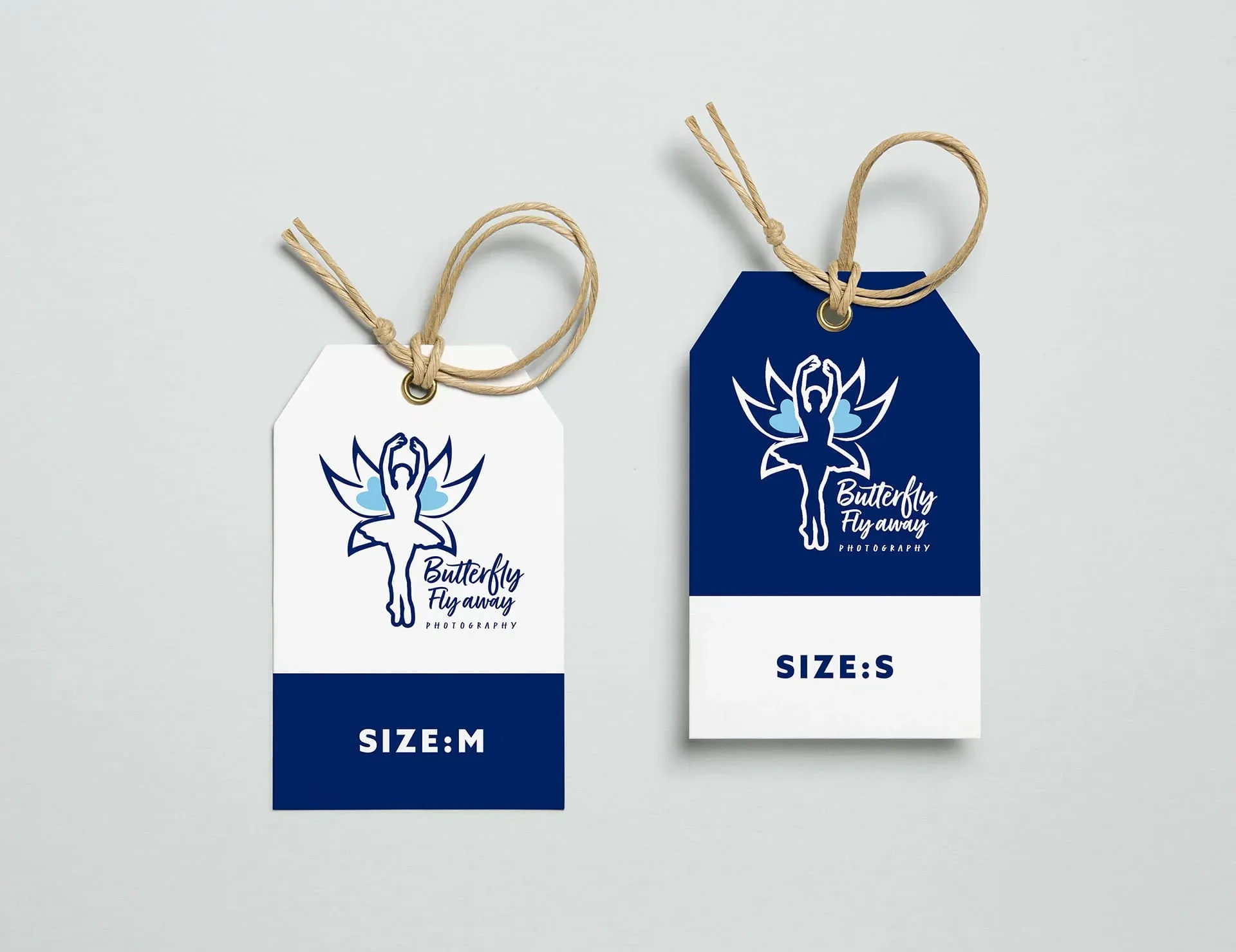 Two tags with a logo and text, likely for a clothing brand or product. The tags are white and blue, with a beige string attached to the top. The logo features a stylized butterfly with wings spread wide. Butterfly Fly Away Photography